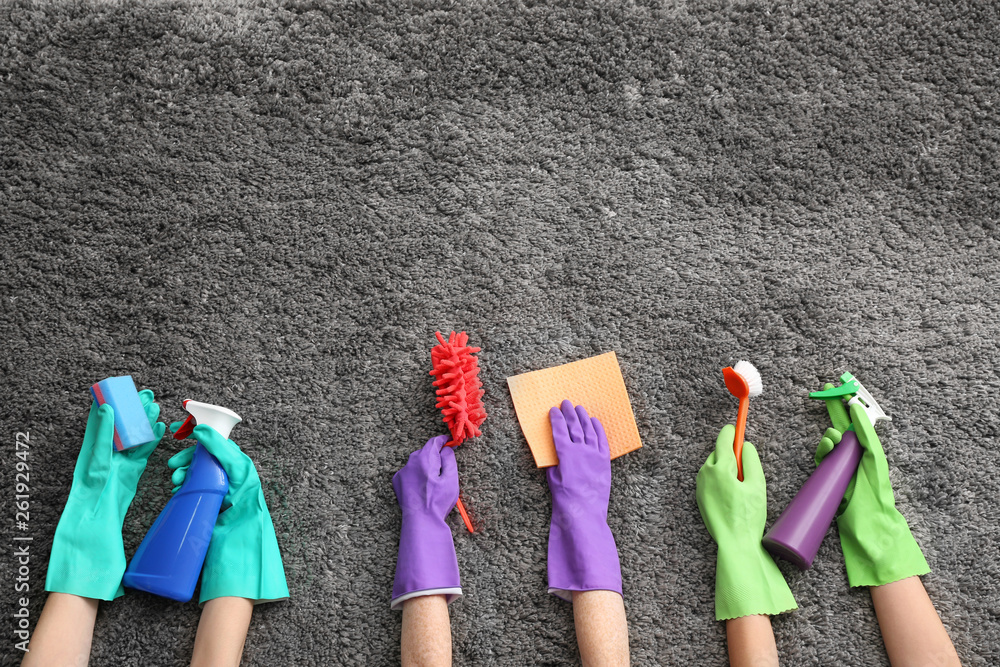 Hands with cleaning supplies on soft carpet