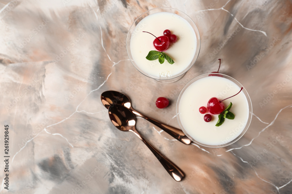 Glasses of delicious panna cotta on color table