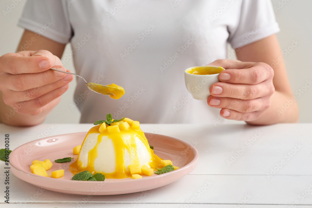 Woman decorating tasty panna cotta at table