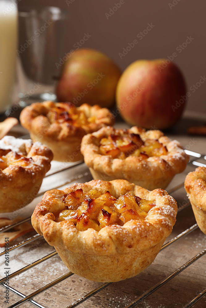 Cooling rack with tasty apple pies on table