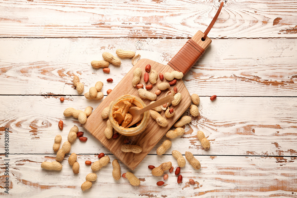 Jar with tasty peanut butter on white table