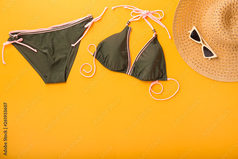 Female swimsuit with hat and sunglasses on color background