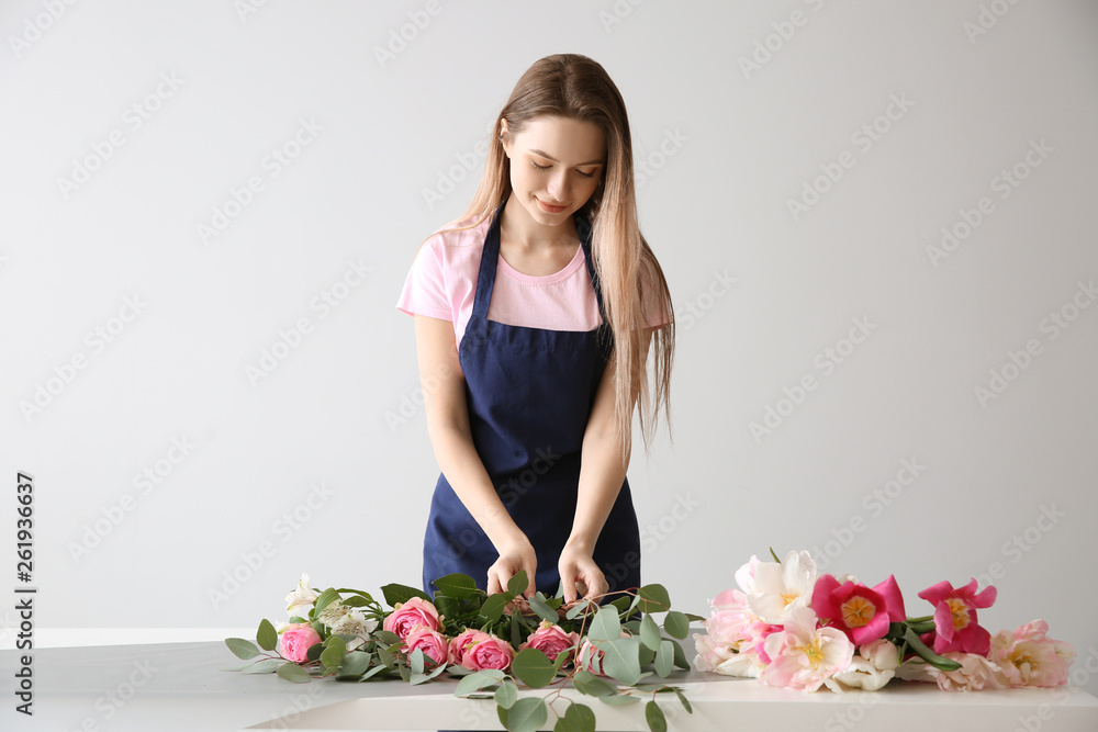 花艺师在灯光背景下在餐桌上制作花束