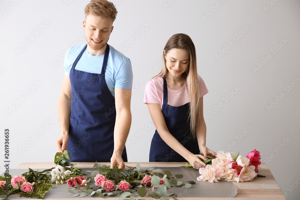 Florists making bouquet at table against light background