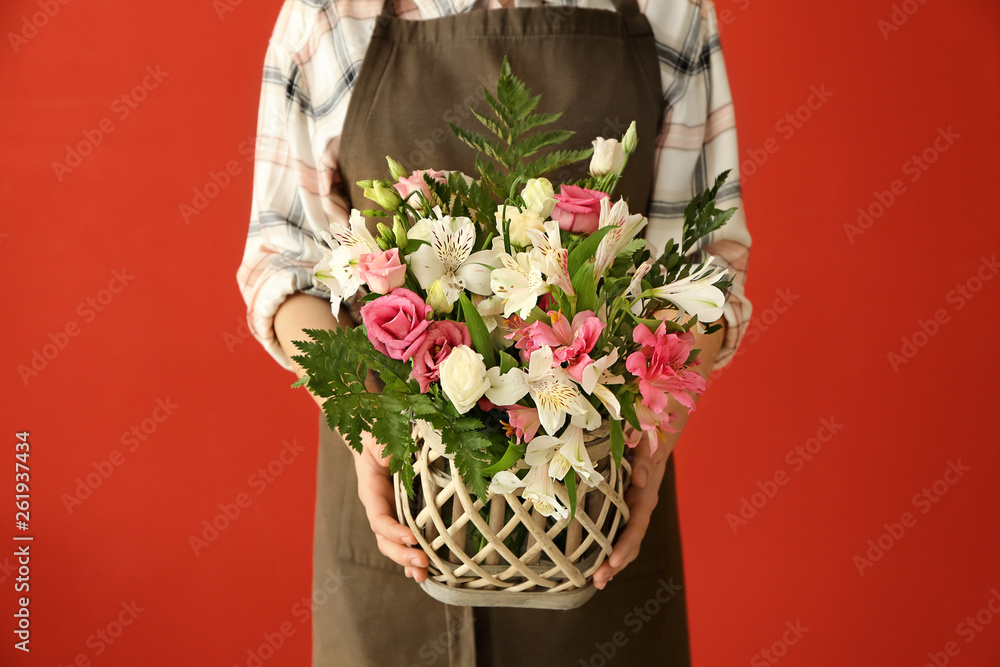 Florist holding beautiful bouquet on color background