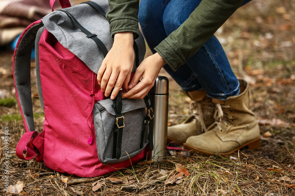 背着背包和保温瓶的女人在森林里旅行