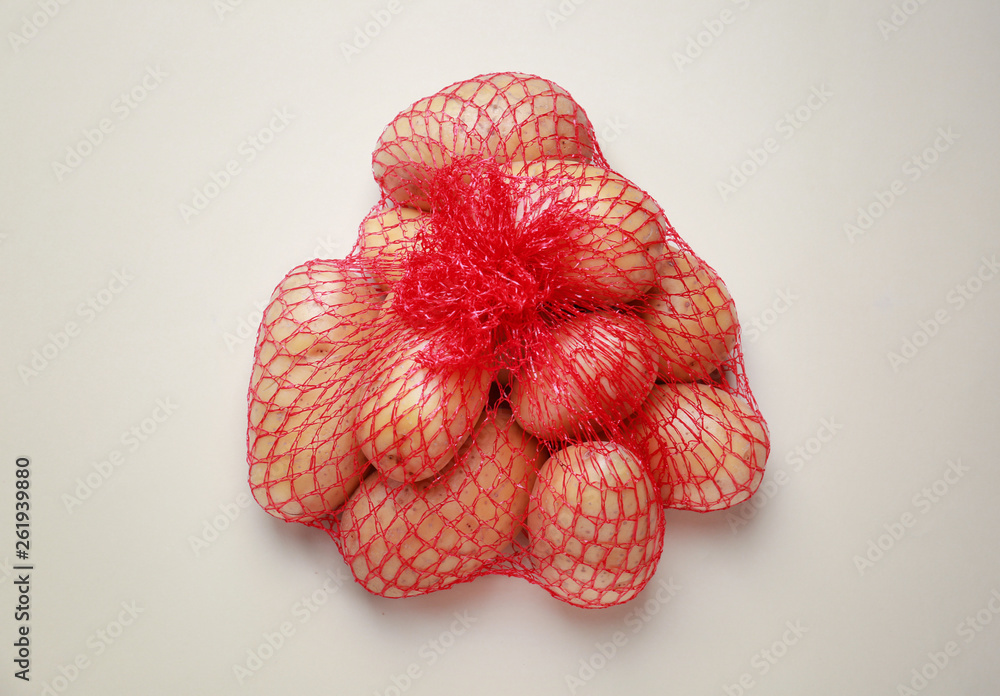 Mash bag with raw potatoes on light background