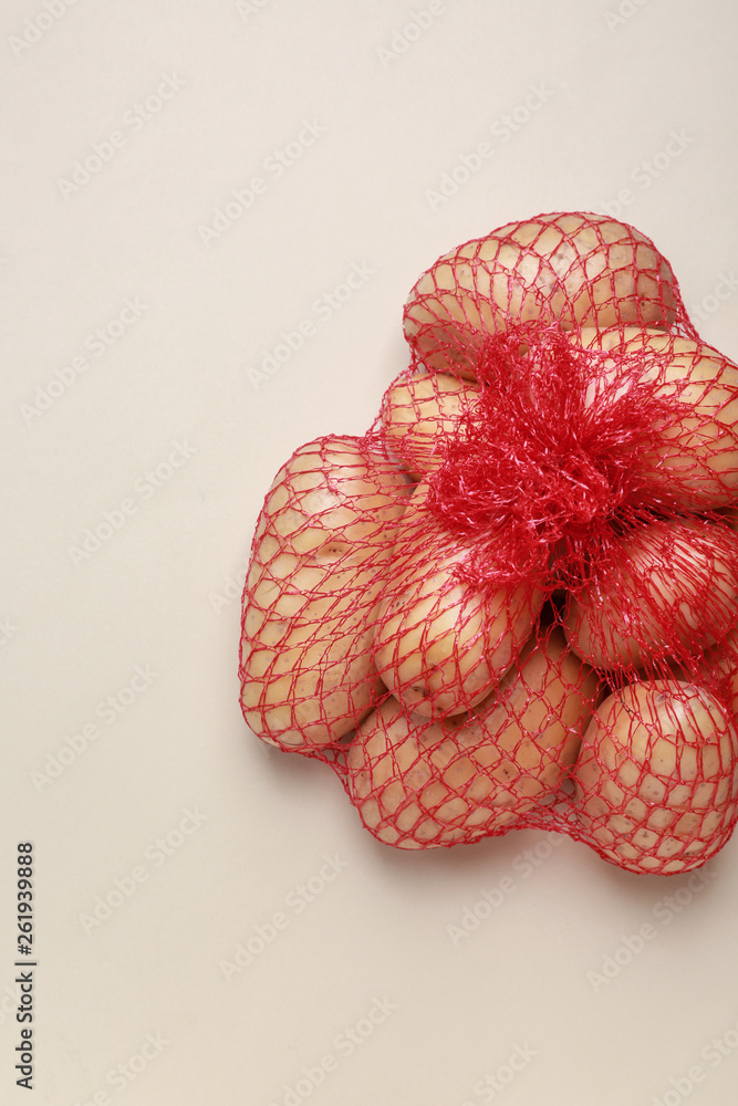 Mash bag with raw potatoes on light background