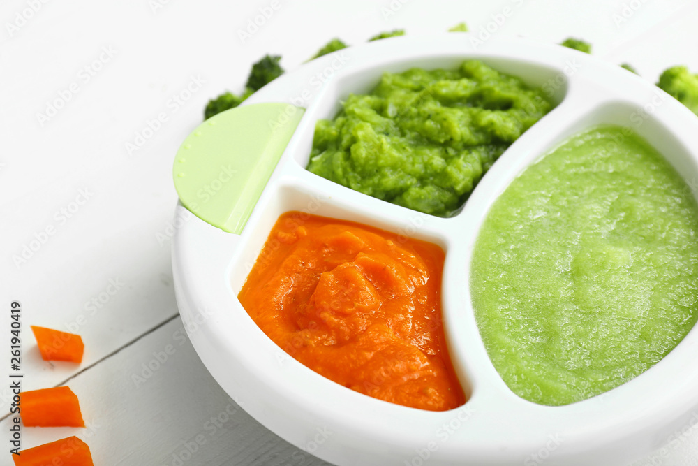 Plate with different healthy baby food on white wooden table