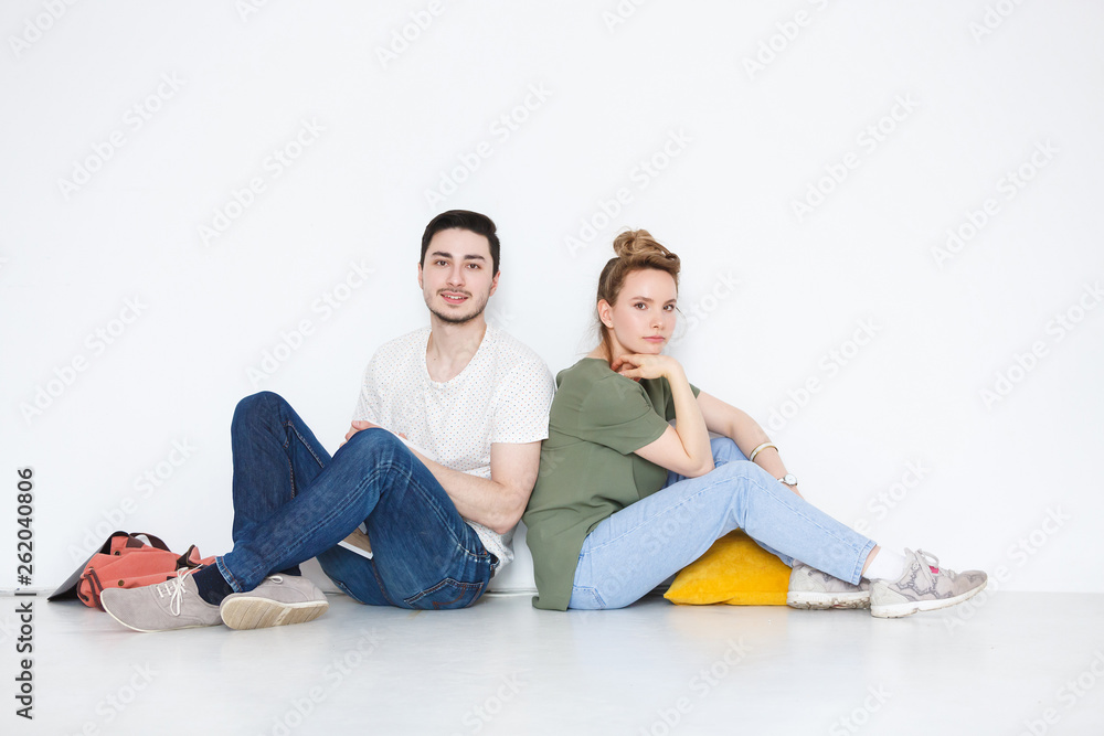 Concept of young teenagers and millenials. Beautiful young girl and cute guy sit on the floor and lo