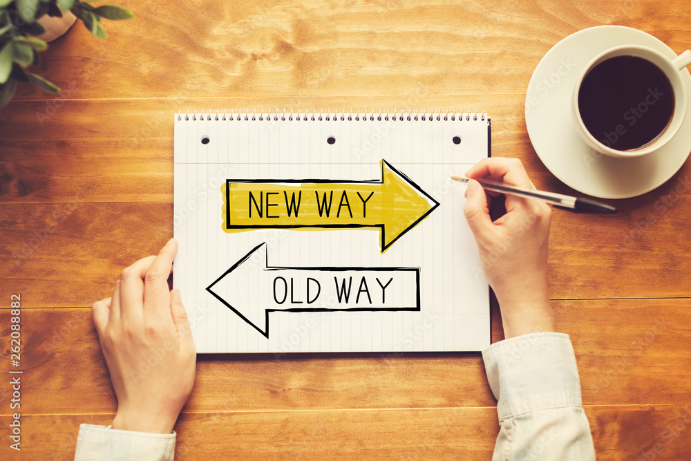 Old way or new way with a person holding a pen on a wooden desk