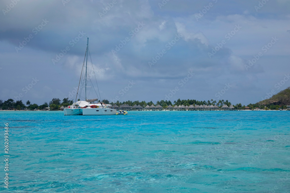 AERIAL Flying towards a luxury yacht anchored in front of overwater villa resort