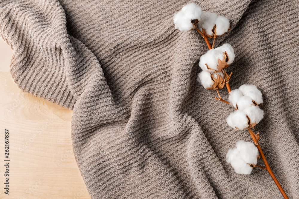 Cotton flowers with knitted plaid on table