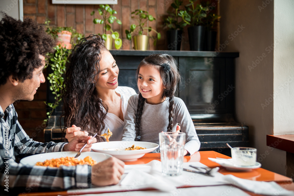 Happy african american family eating lunch together at restaurant and having fun