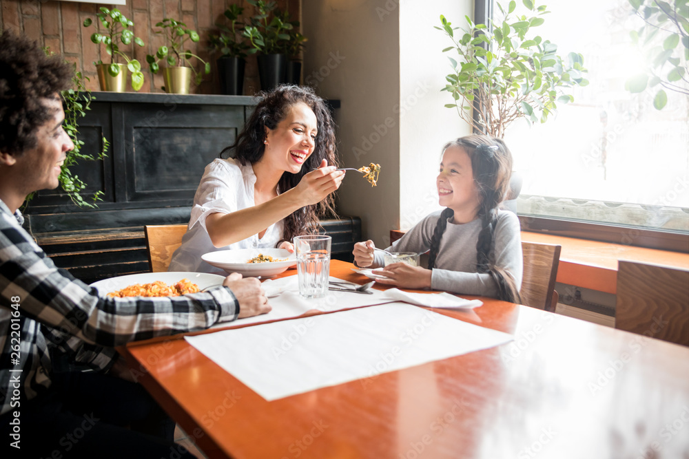 Happy african american family eating lunch together at restaurant and having fun