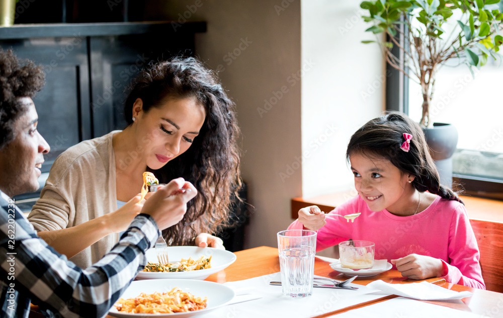 Happy african american family eating lunch together at restaurant and having fun