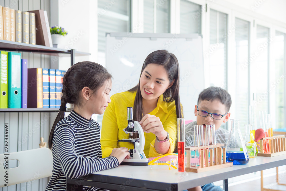 Beautiful asian female teacher teaching students in school library