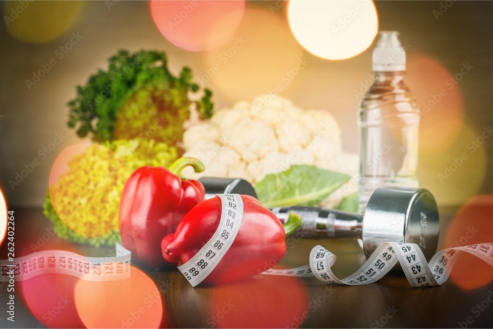 Dumbbell with bottled water , measuring tape and vegetables isolated on white background