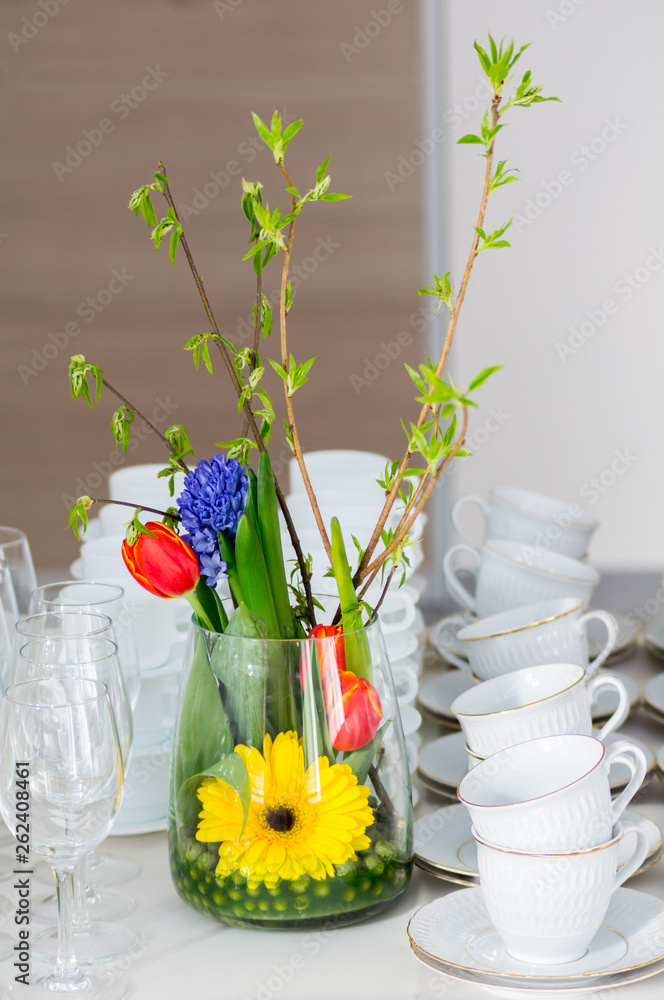 带酒杯和白杯子的自助餐桌上放着鲜花的花瓶