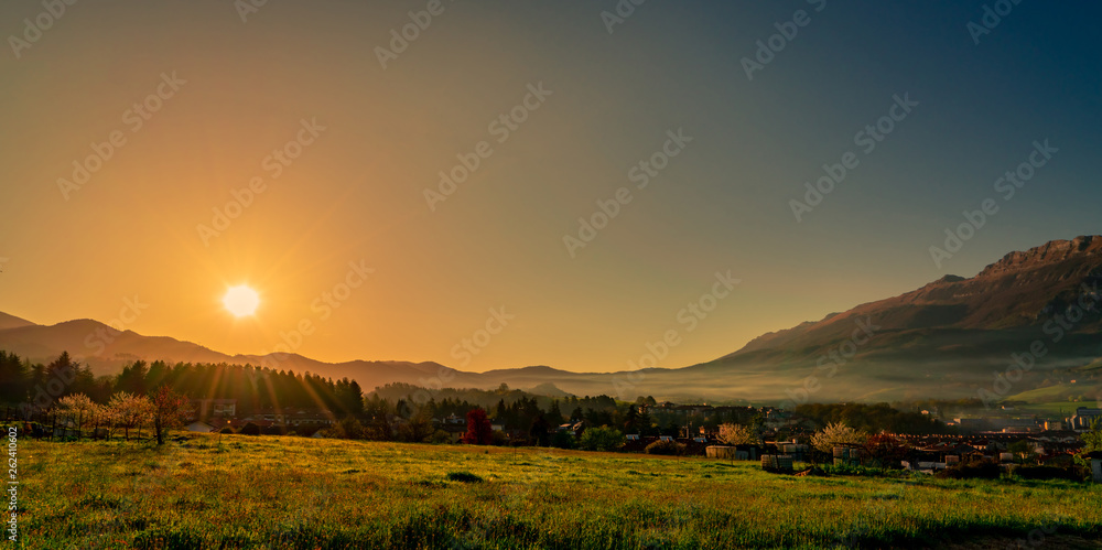 Morning sunrise over the mountain with clear blue sky. Grass field and pine forest in rural village 