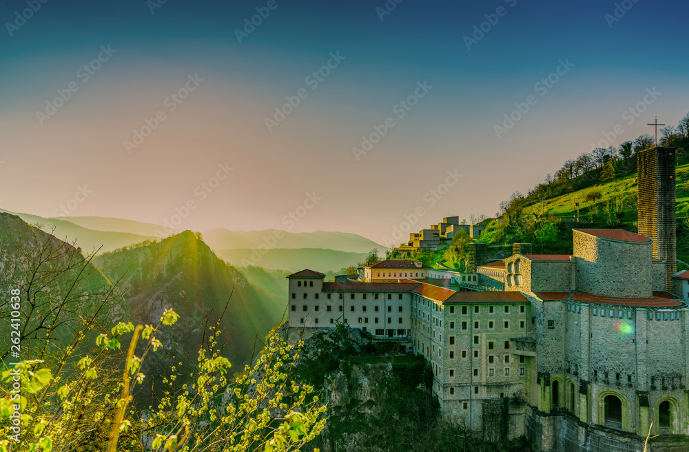 Old building at the edge of rock mountain in the morning with sunrise sky. Mountain range with fog i