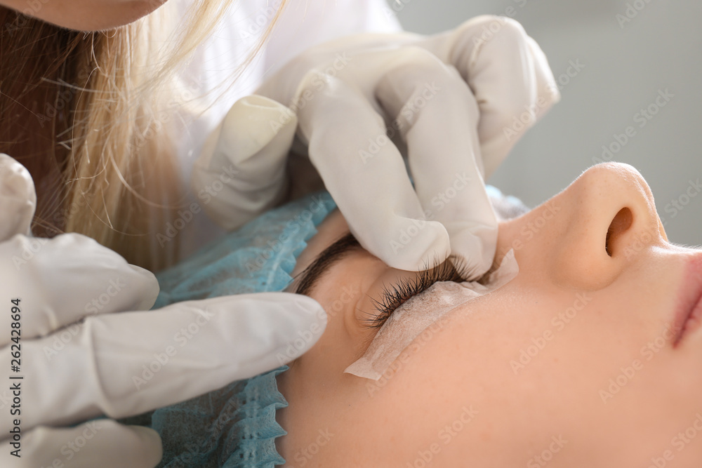 Young woman undergoing procedure of eyelashes lamination in beauty salon, closeup