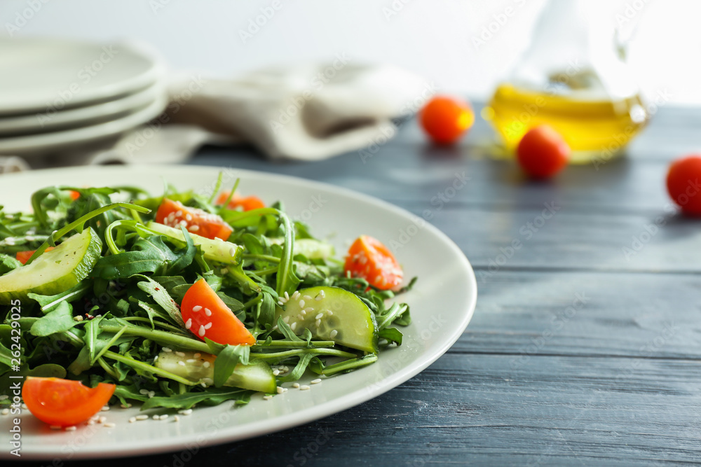 Plate with tasty arugula salad on table