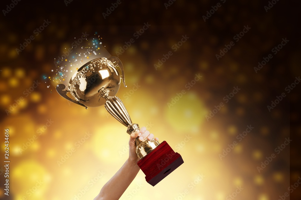 Close-up human hand holding golden Trophy on blurred  background