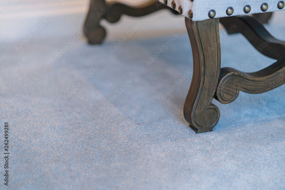 close up wooden leg of armchair on carpet rug in living room