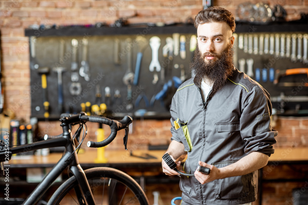 Portrait of a handsome cheerful repairman in workwear at the bicycle workshop