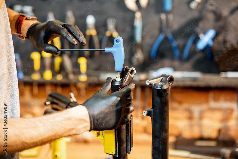 Man disassembling shock absorber of a bicycle fork at the workshop, close-up view