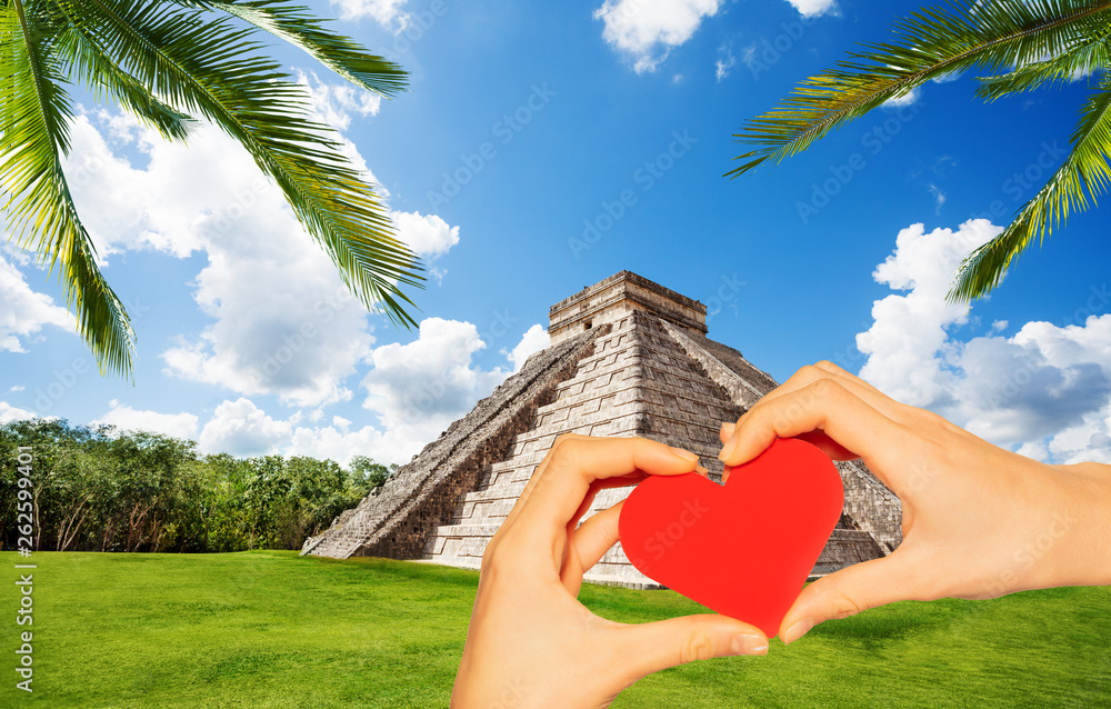 Hand hold red heart in Chichen Itza pyramid Mexico