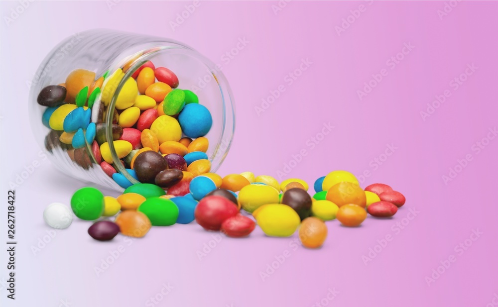 Colorful candies sweets falling out of a glass jar, composition isolated over the white background