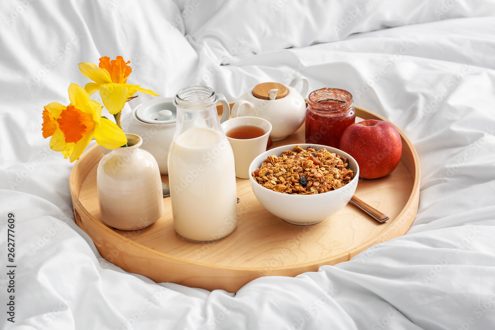 Tray with tasty breakfast on bed