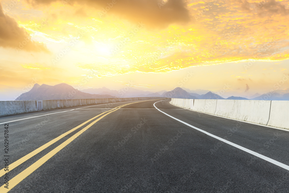 Empty asphalt road and mountains with beautiful clouds at sunset