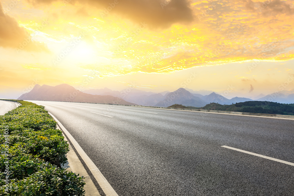 Empty asphalt road and mountains with beautiful clouds at sunset