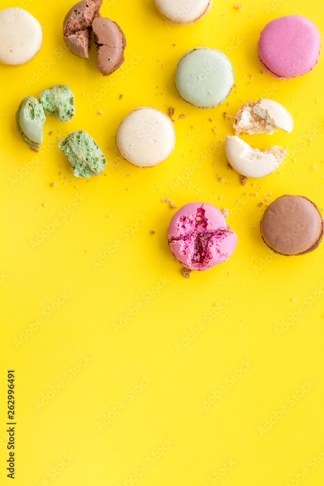 Brignt macarons for sweet break on yellow background top view mock up