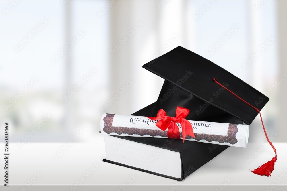 Graduation mortarboard on top of stack of books on  background