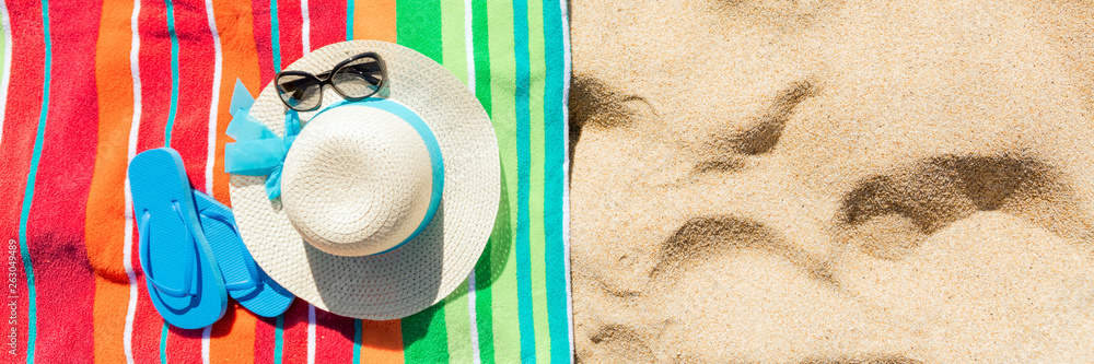 Multi colored beach towel with beach accessories on yellow sand