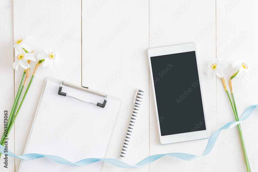 Flat lay blogger or freelancer workspace with a mockup clipboard and white daffodils on a white wood