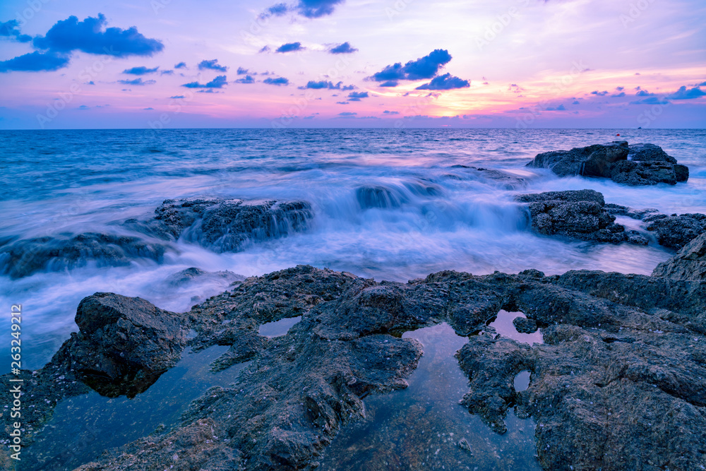 Long exposure image of Dramatic sky and wave seascape with rock in sunset scenery background