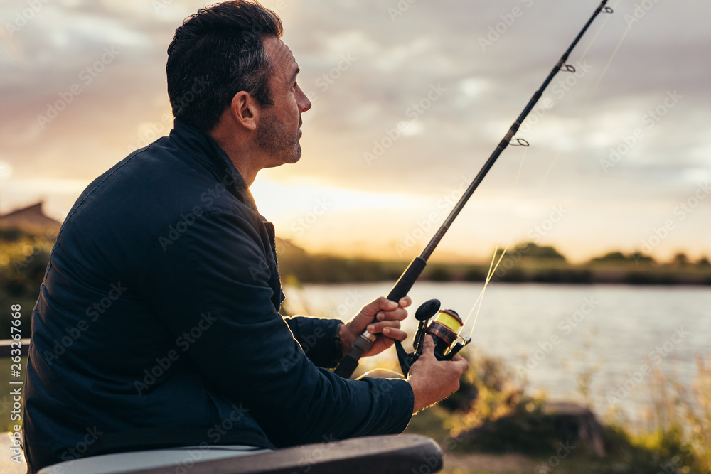 Man sitting near a lake with fishing rod