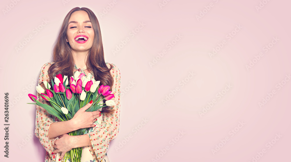 Beauty girl holding spring tulips. Happy beautiful woman receiving a bouquet of colorful tulip flowe