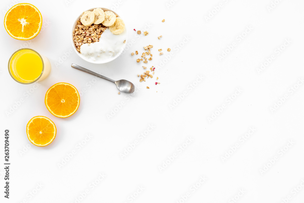 granola with banana slices and orange juice for breakfast on blue background top view copyspace