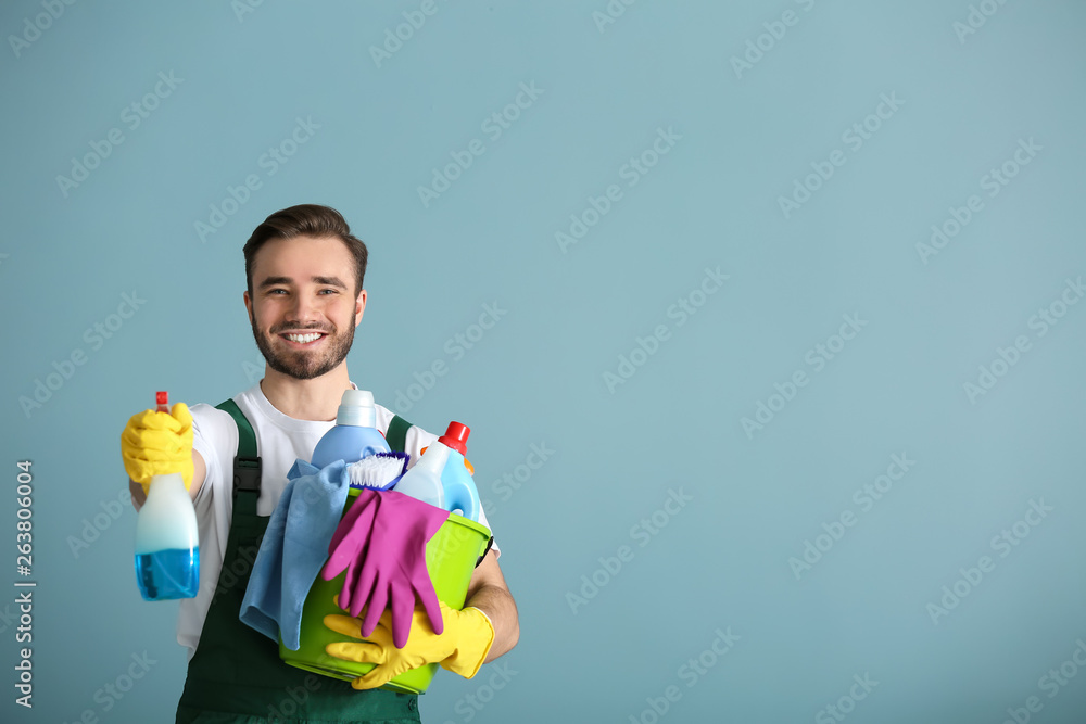 灰色背景下带清洁用品的男性看门人肖像