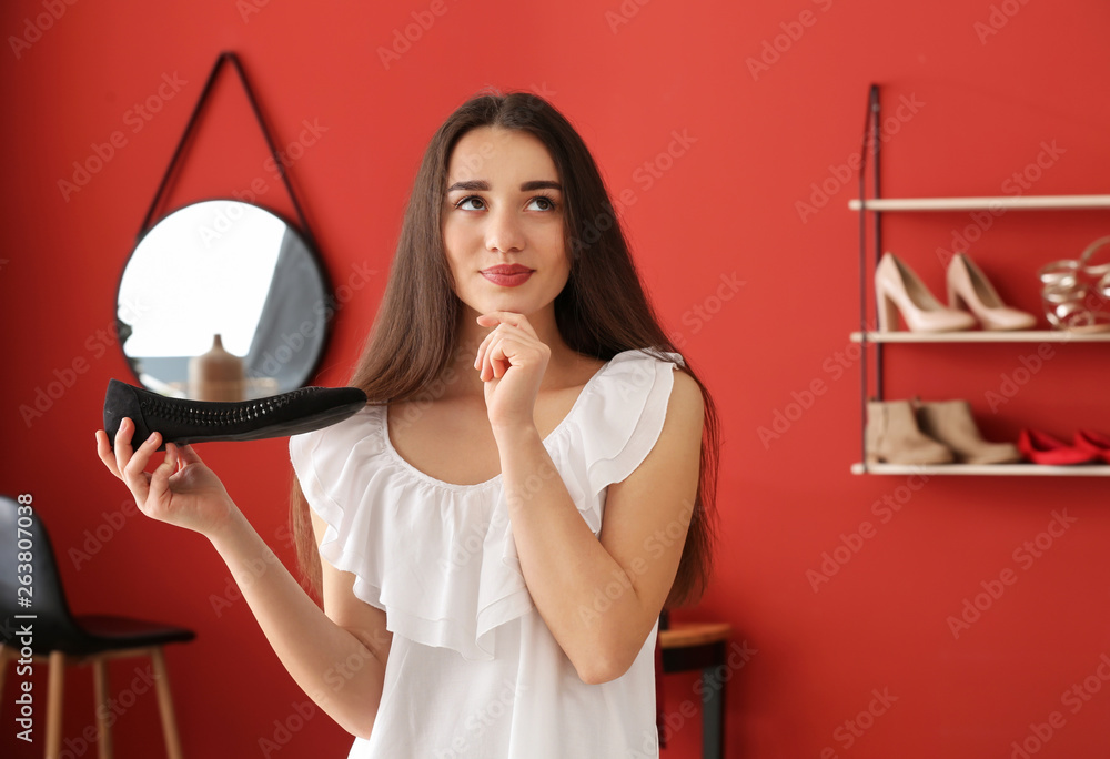 Thoughtful young woman with stylish shoe in dressing room