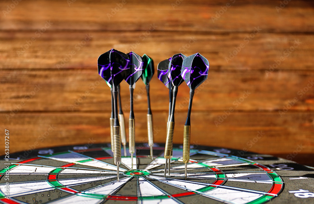 Dartboard with darts on wooden background