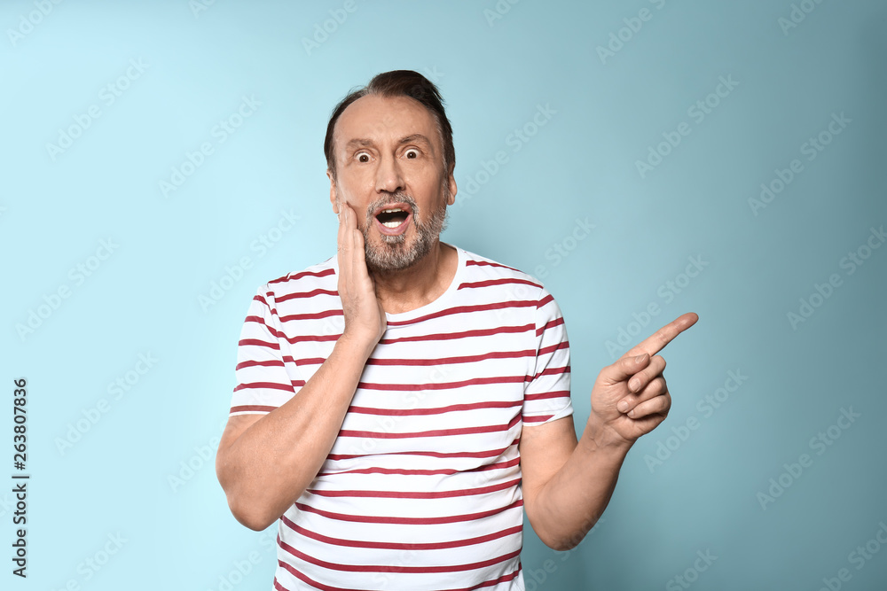 Portrait of shocked mature man on color background