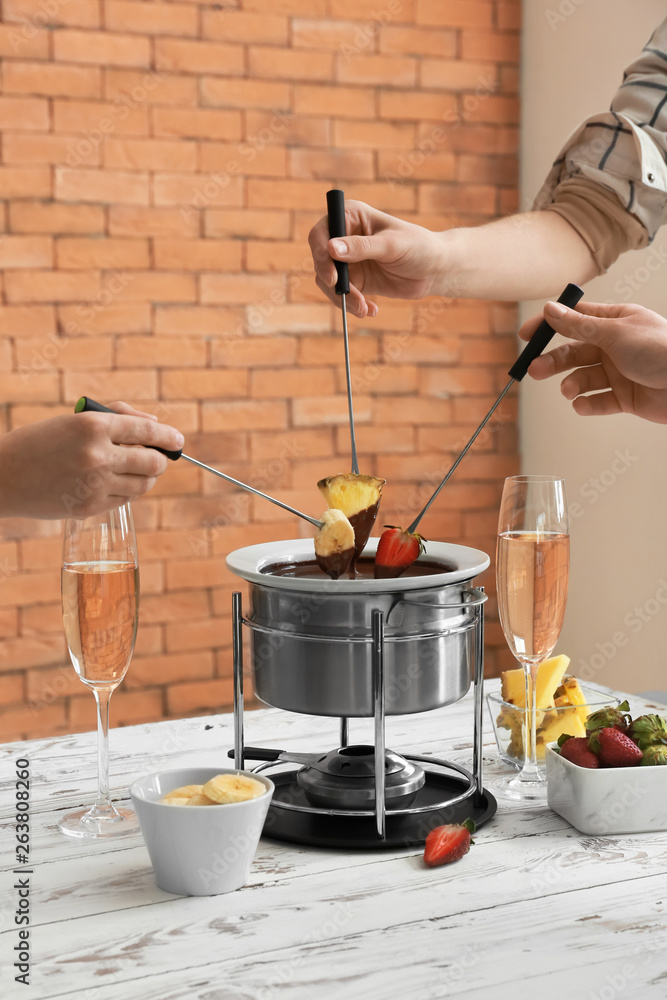 Women dipping fresh fruits into chocolate fondue