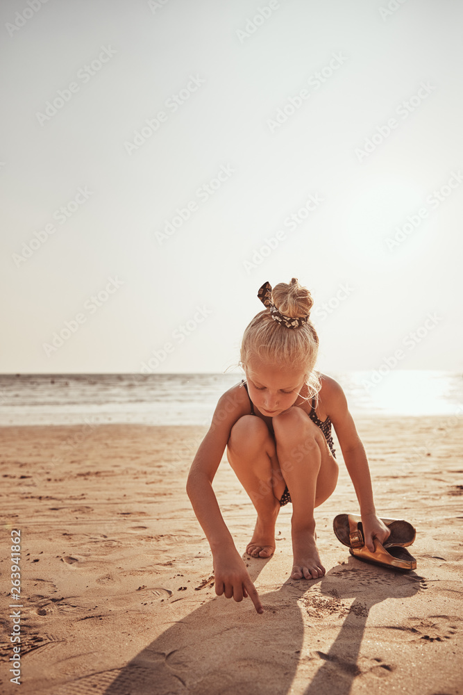 Cute little girl playing on a beach in the summer